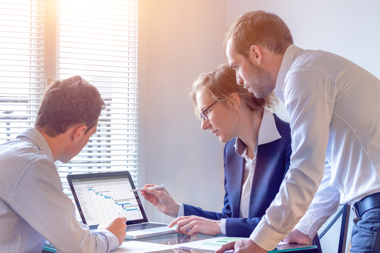 Project manager meeting with team to decide on planning milestones, 3 people in office